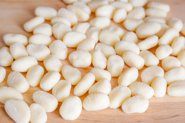 Traditional gnocchi, handmade italian pasta, with tomatoes on wooden table, natural light