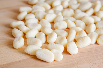 Traditional gnocchi, handmade italian pasta, with tomatoes on wooden table, natural light