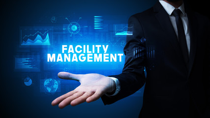 Hand of Businessman holding FACILITY MANAGEMENT inscription, business success concept