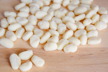 Traditional gnocchi, handmade italian pasta, with tomatoes on wooden table, natural light