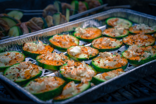 Zucchinischeiben mit Feta &uuml;berbacken und Schweinelendchen Spie&szlig;e auf einem Kohlegrill