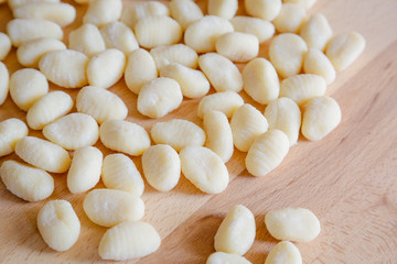 Traditional gnocchi, handmade italian pasta, with tomatoes on wooden table, natural light