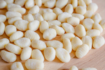 Traditional gnocchi, handmade italian pasta, with tomatoes on wooden table, natural light