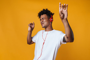 Image of excited african american guy listening music with headphones