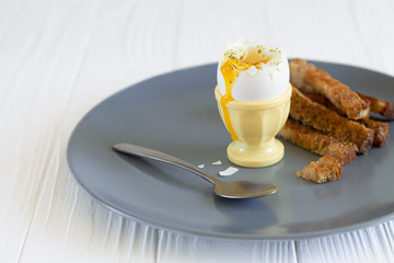 Soft boiled runny egg in an eggcup with toasted bread for breakfast