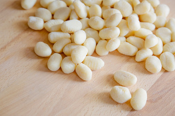 Traditional gnocchi, handmade italian pasta, with tomatoes on wooden table, natural light