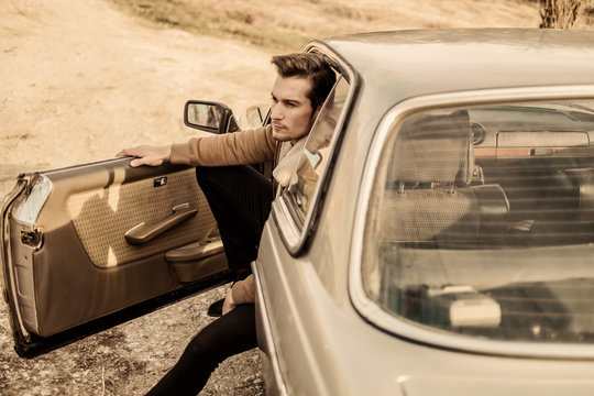 A handsome man driving an oldtimer car.