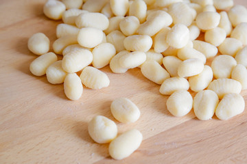 Traditional gnocchi, handmade italian pasta, with tomatoes on wooden table, natural light