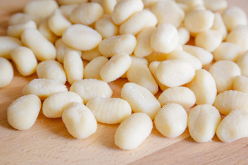 Traditional gnocchi, handmade italian pasta, with tomatoes on wooden table, natural light