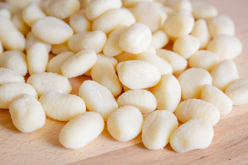 Traditional gnocchi, handmade italian pasta, with tomatoes on wooden table, natural light