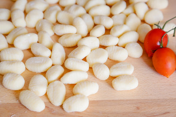 Traditional gnocchi, handmade italian pasta, with tomatoes on wooden table, natural light