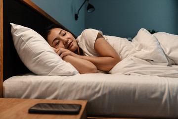 Smiling young asian woman sleeping in bed