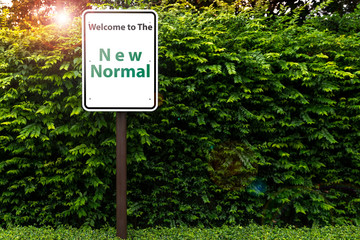 Signage with message “ Welcome to the New Normal” on green trees Background. Corona virus...
