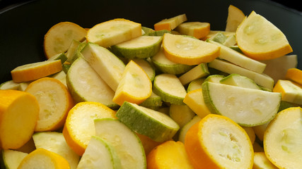 Green zucchini and zucchini in a black wok. Vegan food.	
