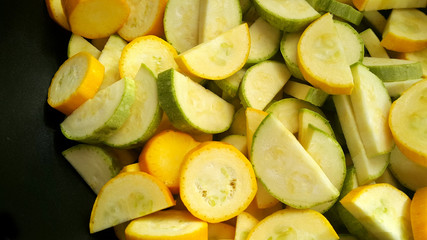 Green zucchini and zucchini in a black wok. Vegan food.