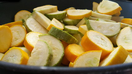 Green zucchini and zucchini in a black wok. Vegan food.