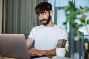 Handsome young bearded man working on laptop computer