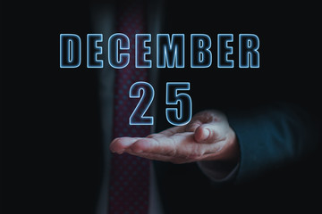 december 25th. Day 25 of month, announcement of date of  business meeting or event. businessman holds the name of the month and day on his hand.. winter month, day of the year concept