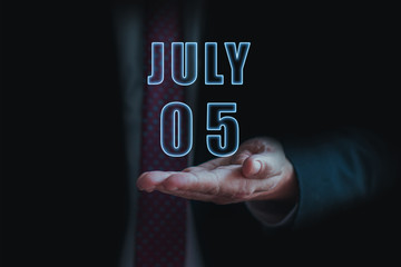 july 5th. Day 5 of month, announcement of date of  business meeting or event. businessman holds the name of the month and day on his hand.. summer month, day of the year concept