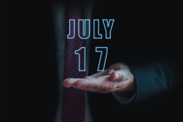 july 17th. Day 17 of month, announcement of date of  business meeting or event. businessman holds the name of the month and day on his hand.. summer month, day of the year concept