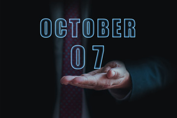 october 7th. Day 7 of month, announcement of date of business meeting or event. businessman holds the name of the month and day on his hand. autumn month, day of the year concept