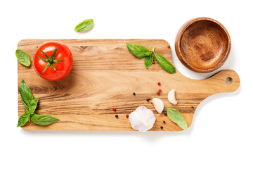 Cutting wooden board with ingredients:  tomatoes, basil, garlic and pepper isolated on white background.