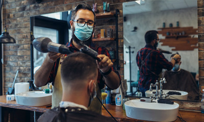 Hair cutting during pandemic. Young man have hair cutting at barber shop during pandemic isolation, they both wear protective equipment.