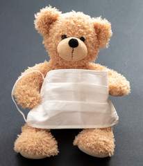 Coronavirus and pollution protection concept. Teddy bear with protective face mask on gray background