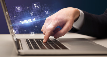 Obraz na płótnie Canvas Businessman working on laptop with PREMIUM inscription, online shopping concept