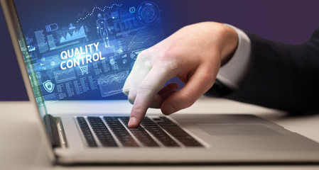 Obraz na płótnie Canvas Businessman working on laptop with QUALITY CONTROL inscription, cyber technology concept