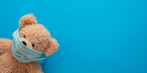 Coronavirus and pollution protection concept. Teddy bear with protective face mask on blue background