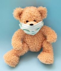 Coronavirus and pollution protection concept. Teddy bear with protective face mask on blue background