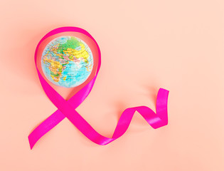 Globe and pink ribbon. The symbol of the world day against cancer. The concept of fighting cancer