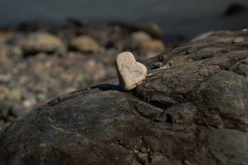A stone in the form of a heart stands on a stone against a background of water