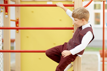 Boy in strict suit plays on the stairs at school on the first day