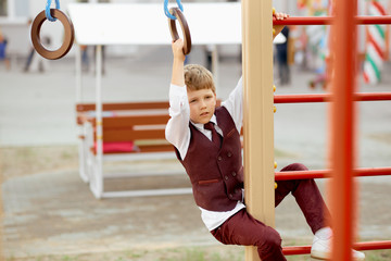 Boy in strict suit plays on the stairs at school on the first day