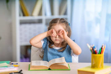 child is tired of learning. home schooling, homework. girl rubs his eyes