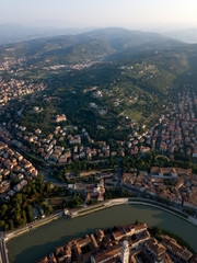 Aerial view of Florence Firenze, Italy. Houses with tiled orange roofs, bend of Arno river embankment, Tuscany green hills, mountains, cypress trees, sky.