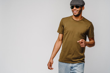 african-american young man in green t-shirt wearing sunglasses and cap over light grey background with copy space