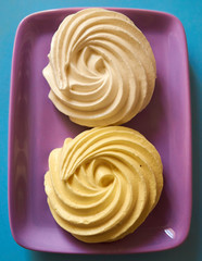 Set of two meringue cakes on a purple saucer