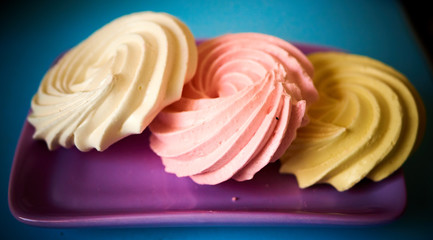 Set of three bright cakes on a purple saucer