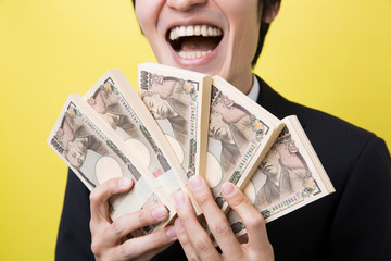 札束を持ち喜ぶ男性