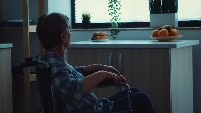 Sad depressed disabled senior woman in silhouette sitting in a wheelchair. Elderly handicapped pensioner after injury and rehab, paralysis and disability for depressed invalid full of sorrow, worry
