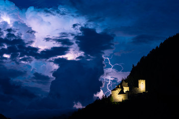 Lightning bolt strikes down from a stormcloud, close to a castle in the mountains