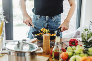 Young woman cooking vegetables at home kitchen