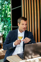 Handsome businessman dressed in the suit drinking wine. Businessman enjoying in the restaurant.