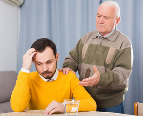 Old father is serious conversation with his son at home