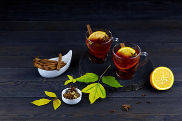 Mulled wine with slice of orange and spices on a dark rustic wooden background. Autumn drink or...