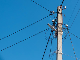 Concrete pole with lantern and lots of electric wires