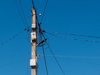 Concrete pole with lantern and lots of electric wires